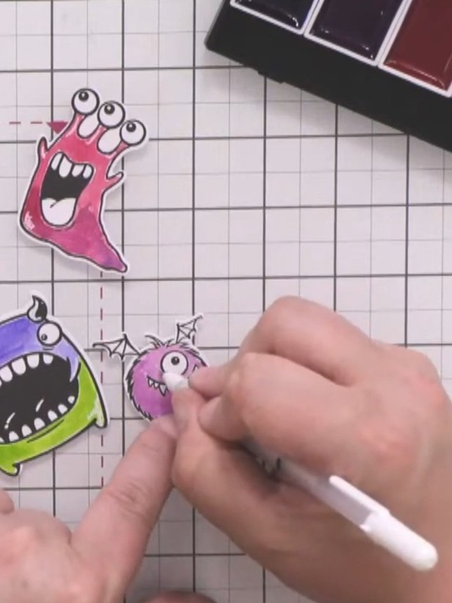 Step 11: Die-cut the coloured monster images using their corresponding dies. Add white gel pen details to each monster 