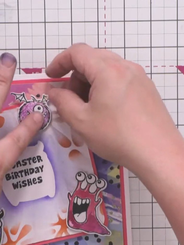 Step 12: Arrange and adhere the three coloured monster characters around the card front. Position one purple furry mons
