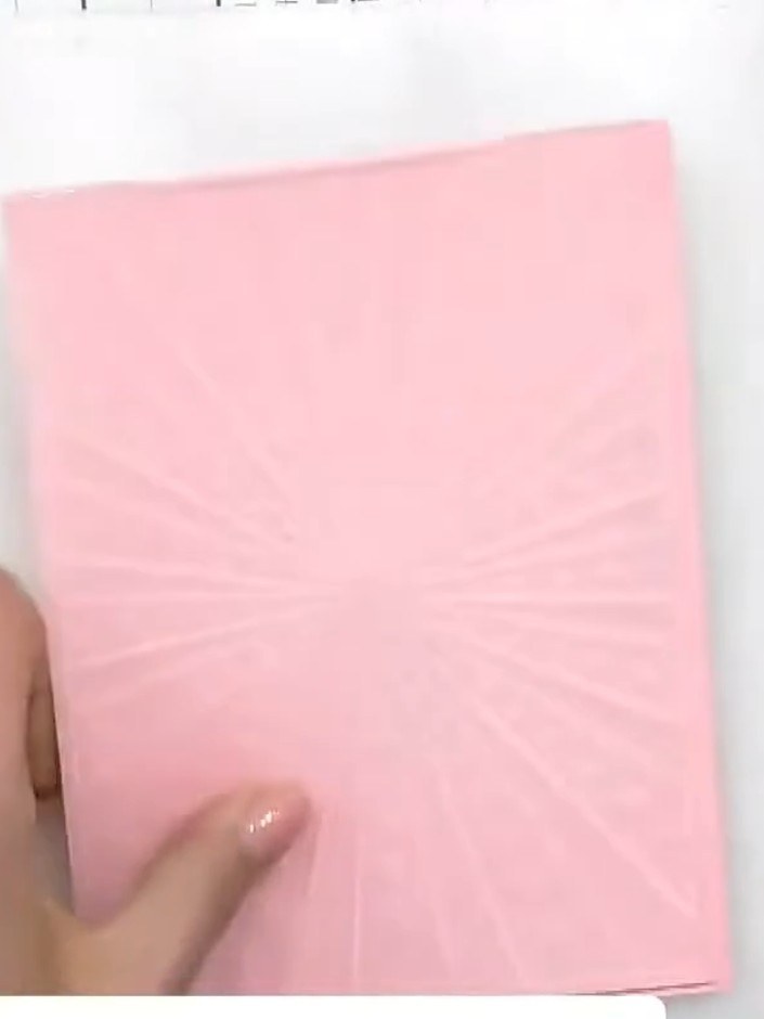 Step 1: Elige un trozo de cartulina rosa para la base de tu tarjeta. Colócalo sobre tu tapete de corte, listo para el siguiente paso.