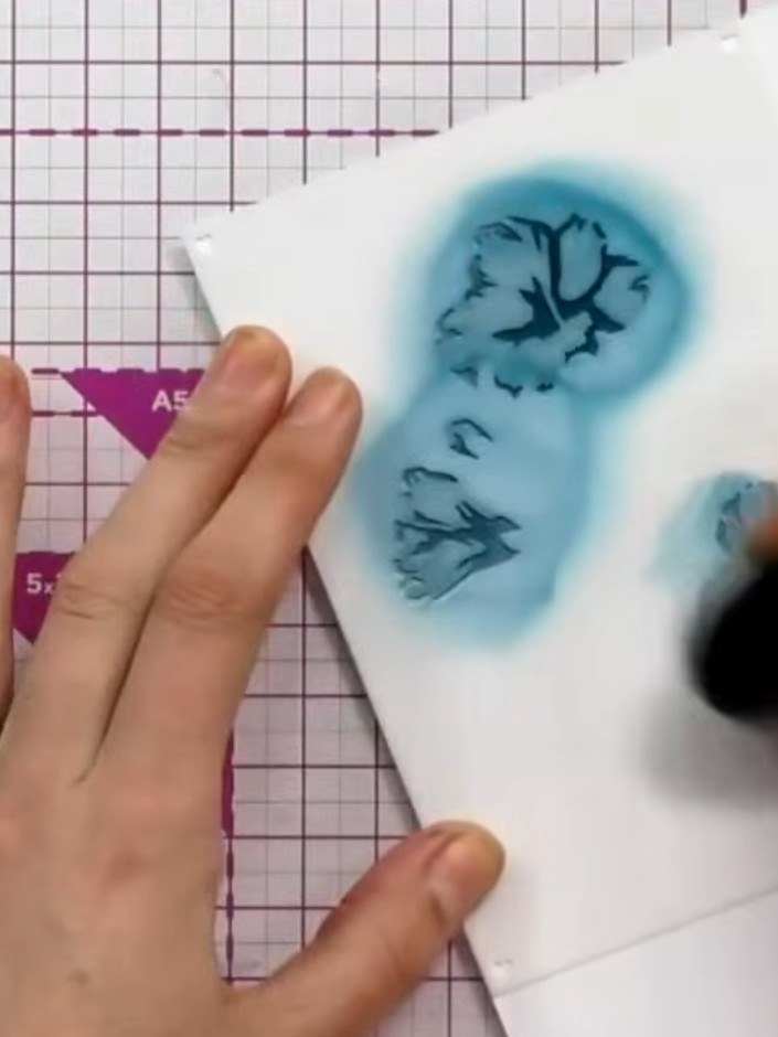 Step 2: Apply the second stencil with the same teal ink, pressing slightly harder to build up the colour depth and cre