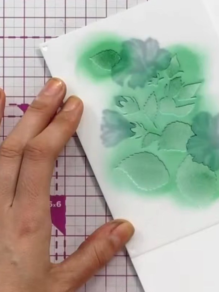 Step 4: Using a green ink pad, apply stencils four and five to create foliage and stem details on your card. The green