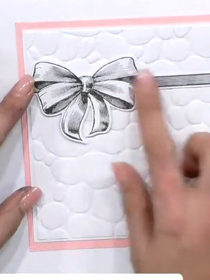 Step 4: Add a stamped bow embellishment to the centre top of the white embossed panel. Position it centrally above the