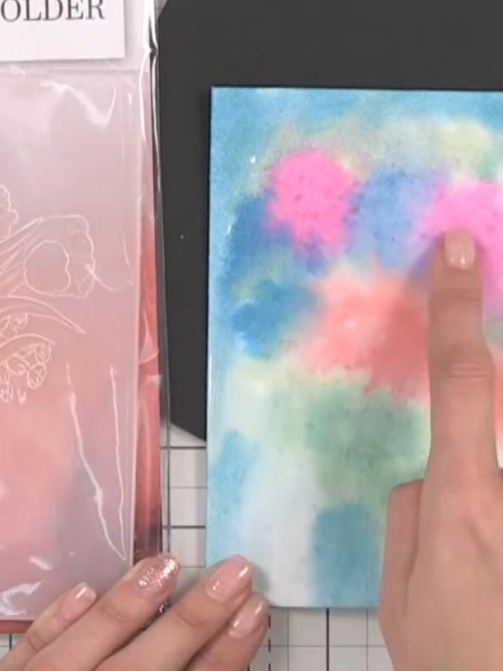 Step 1: Apply watercolour paint to a piece of card, using pink, blue, and green colours. Drop the colours where the em