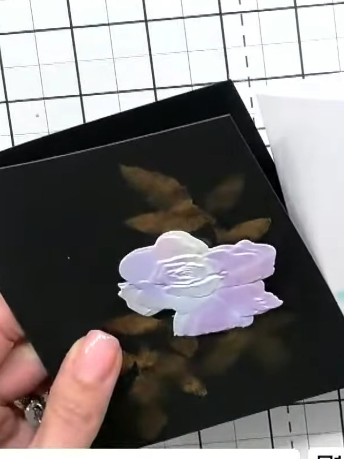 Step 4: Position the embossed flower pieces onto the black card, layering them to create depth and dimension. Arrange 