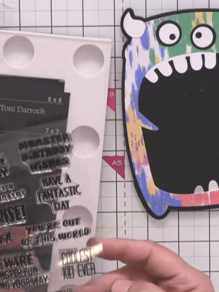 Step 10: Using the stamping platform, stamp a sentiment from the monster stamp set onto white card using black ink. Cho