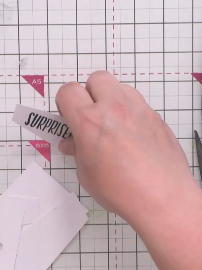 Step 11: Trim around the 'SURPRISE!' sentiment piece with an abstract edge. Glue it onto a black card scrap and trim ar
