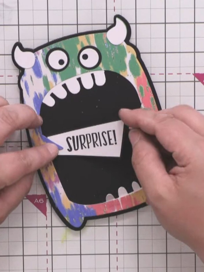 Step 12: Attach the sentiment piece to the monster using a foam pad to raise it up. Position it under the monster's arm