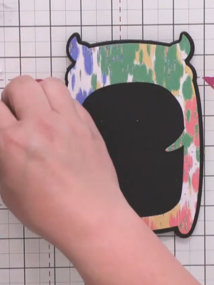 Step 7: Die cut a black circle from black card. Position and attach the black circle in the centre of the monster's fa