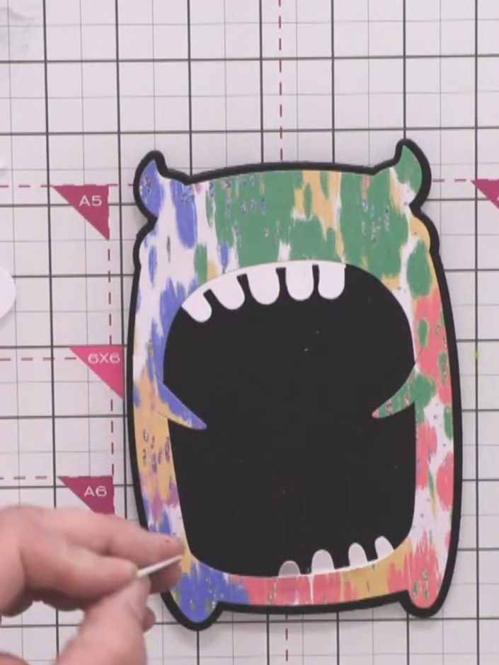 Step 8: Position the horn pieces at the top corners of the monster head. Apply glue to secure them in place, ensuring 
