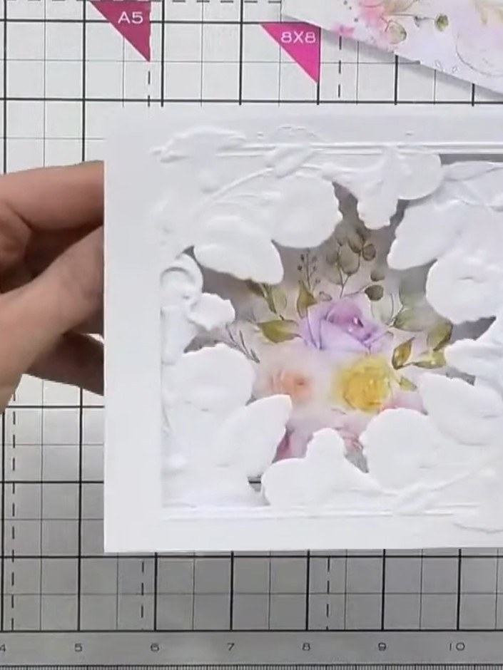 Step 5: Trim away any excess paper from the floral mount that overhangs the embossed frame, ensuring the design sits n
