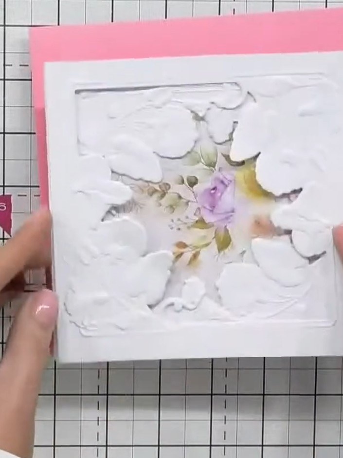 Step 6: Position the layered floral design onto the pink card base, ensuring the floral element shows through the aper